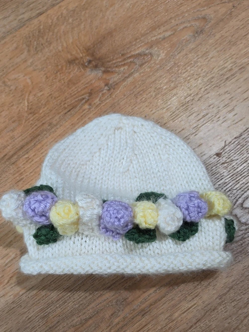 Hand-Knitted Cream Baby Hat with Pastel Flower Trim
